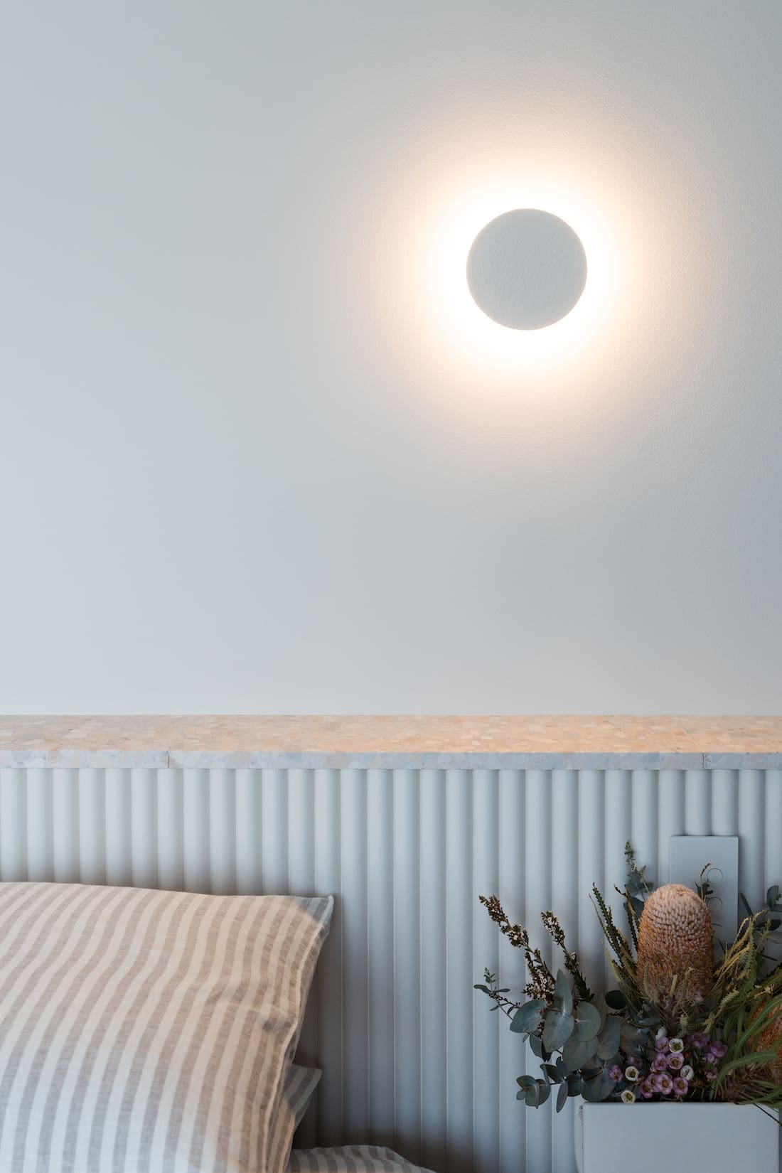 Round wall light add ambience to the minimalist modern bedroom