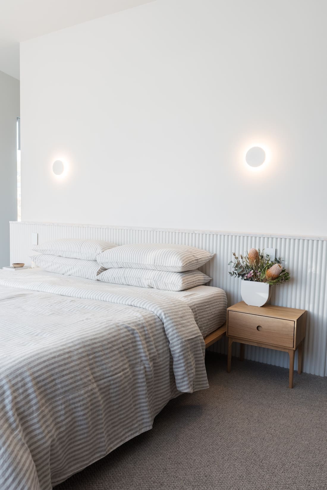 White fluted wall ledge with terrazzo top is an alternative feature wall idea in a minimalist modern bedroom
